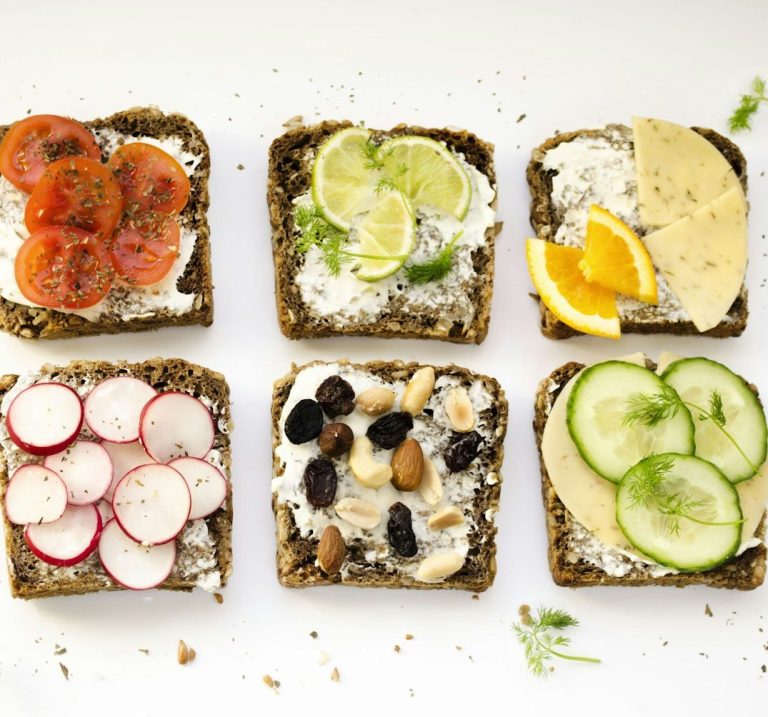 Gesunde Pause Sechs belegte Brote mit verschiedenen Toppings: Gemüse, Früchte und Nüsse.