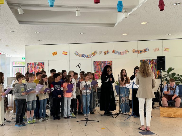Bandklasse Impression Kinderchor singt in einem hellen Raum, umgeben von kunterbunten Kunstwerken.