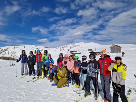 Erasmus+ Gruppenfoto Skiausflug Gruppe von Skifahrern in Winterkleidung auf schneebedecktem Hang mit blauem Himmel.
