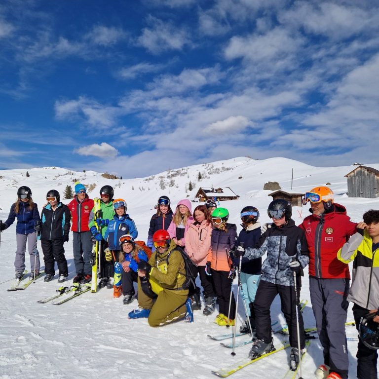 Erasmus+ Skiausflug Gruppe von Skifahrern unterschiedlicher Altersgruppen auf Schnee mit Bergen im Hintergrund.
